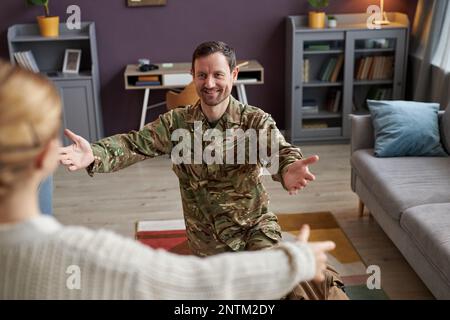 Ritratto di felice papà militare tornando a casa e abbracciando la figlia a braccia aperte Foto Stock
