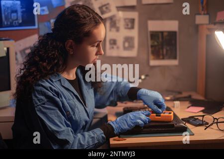 problema di controllo tecnico del computer portatile con multimetro. Riparatore femmina che dismonta la scheda madre del laptop. Tecnico che ripara il computer rotto in corrispondenza del wor Foto Stock