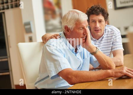 Lì per sostenersi l'un l'altro. Colpo di un uomo che consolava il padre anziano a casa. Foto Stock