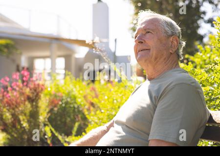 Felice uomo caucasico anziano seduto e a piedi in giardino Foto Stock