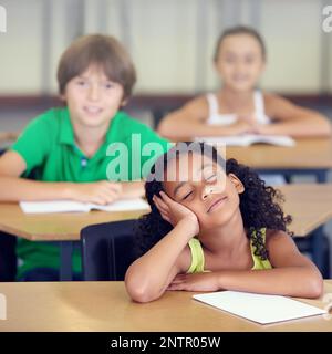 Le sue menti in un altro luogo interamente. Una bambina che sogna durante una lezione scolastica. Foto Stock