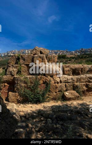 Moderni appartamenti nella città di Agrigento, nella Sicilia meridionale, si affacciano sulla Valle dei Templi, sito dell'antica Akragas greco-romana o Agrigentum, Dove alcuni resti del vasto Tempio di Zeus Olimpio o Giove sono stati intatti derubati di pietra e con mattoni utilizzati in passato per le riparazioni. Foto Stock