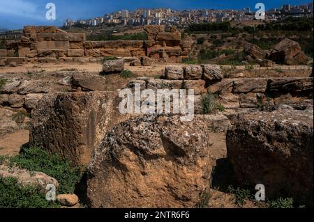 L'antica Grecia incontra l'Italia moderna: I blocchi di appartamenti nella città di Agrigento, nella Sicilia meridionale, si affacciano sulla Valle dei Templi, sede delle antiche Akragas o Agrigentum greco-romane, e sui resti sparsi e intemperati del vasto Tempio di Zeus o Giove Olimpio, costruito intorno al 480 a.C. e una delle più grandi strutture doriche dell'antichità greca. Foto Stock