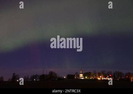 Hagebyhöga, Svezia. 27th, febbraio 2023. Tempo stagionale, aurora boreale durante la notte verso il martedì nella contea di Östergötland, Svezia. Nella foto: La chiesa di Hagebyhöga, appena fuori dalla città di Vadstena, Svezia. Un'aurora (aurora o aurora), nota anche come le luci polari, è un'esposizione di luce naturale nel cielo della Terra, vista prevalentemente nelle regioni ad alta latitudine. Credit: Jeppe Gustafsson/Alamy Live News Foto Stock