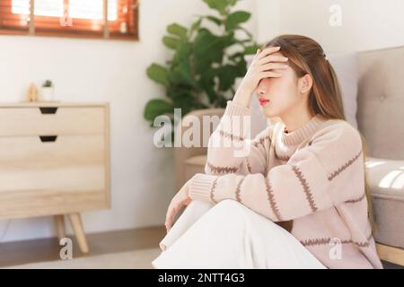 Concetto di tempo di riposo, le donne sono sedute sul pavimento e toccare la fronte dolorante con mal di testa sofferenza. Foto Stock