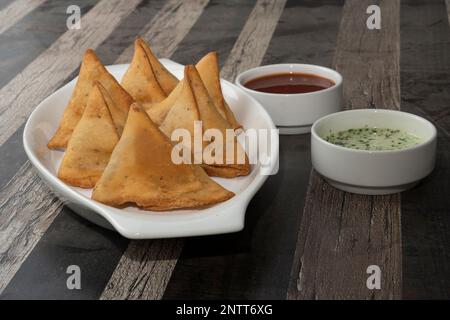 Spuntini di patate Samosa su sfondo testurizzato. Cibo indiano Ramadan, pasto pakistano Iftar. Foto Stock