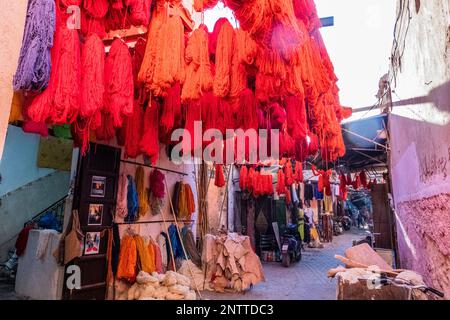 Fili di tessuto di colore rosso appesi ad asciugare per la vendita in un souk a Marrakech Foto Stock