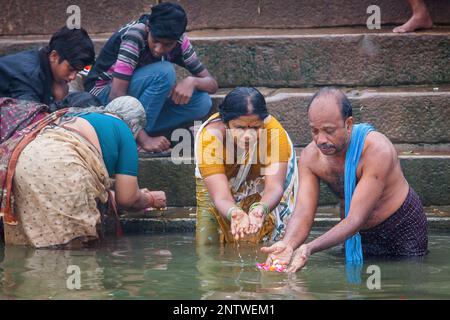 Uomo e donna che fa l'offerta, nel ghats del fiume Gange, Varanasi, Uttar Pradesh, India. Foto Stock