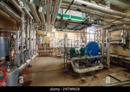 Commutazione industriale di tubi di riscaldamento nel seminterrato con una stazione di pompaggio Foto Stock