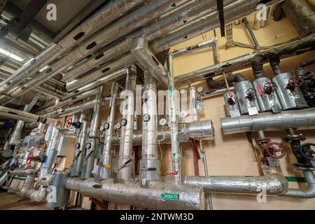 Commutazione industriale di tubi di riscaldamento nel seminterrato che corrono lungo le pareti e il soffitto Foto Stock