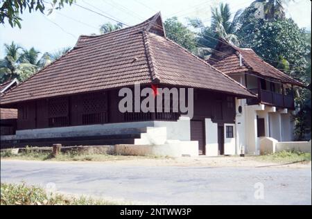 Kerala Case:- la forma visiva più distintiva dell'architettura Kerala è il lungo, ripido tetto inclinato costruito per proteggere le pareti della casa e per resistere al monsone pesante, normalmente posato con piastrelle o labirinto di paglia di foglie di palma, sostenuto su un telaio del tetto in legno duro e legno. Il Kerala è uno stato che riceve le precipitazioni per almeno 6 mesi in un anno e per un tale clima, i tetti inclinati sono sempre i migliori. L'architettura del Kerala segue Thatchu Shasthra, una scienza della Falegnameria che regola le sfumature dell'edificio/costruzione. Foto Stock