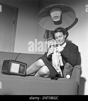 Ascoltatori radio in passato. Una donna si vede seduta in un divano a maglia con una radio sul lato di lei. Sulla parte anteriore della radio è presente una scala e quando si ruota la manopola accanto ad essa in modo che il puntatore si trovi al centro del nome di una stazione, la stazione era lì. Oltre alle trasmissioni FM, hanno anche ascoltato le radio straniere a onde lunghe. Svezia nel 1945 Kristofferson Ref L179-3 Foto Stock