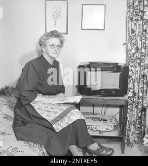 Ascoltatori radio in passato. Quattro giovani donne nello spogliatoio di un teatro di Stoccolma si siedono vestite con i loro abiti da palco e si riuniscono intorno ad un piccolo apparecchio radio, ascoltando con ansia. Sulla parte anteriore della radio è presente una scala e quando si ruota la manopola accanto ad essa in modo che il puntatore si trovi al centro del nome di una stazione, la stazione era lì. Oltre alle trasmissioni FM, hanno anche ascoltato le radio straniere a onde lunghe. Svezia nel 1949 Kristofferson Ref AT25-11 Foto Stock