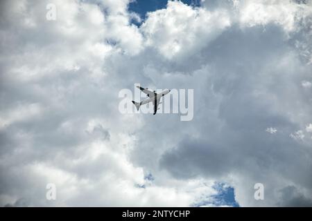 Ripresa a lunga distanza di un aereo direttamente sotto di lui, cielo blu con nuvole sullo sfondo. Foto Stock