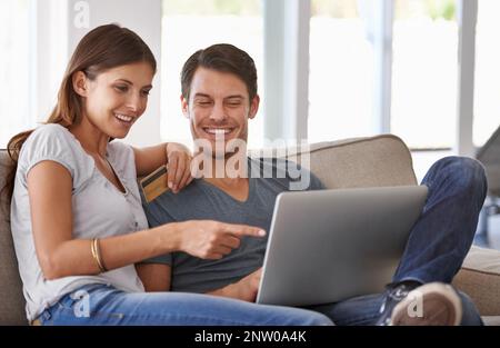Dovremmo ottenere tutto questo. Una giovane coppia affettuosa che fa un po' di shopping online a casa. Foto Stock