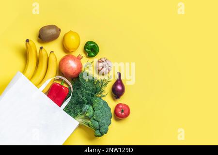 Eco-friendly sacchetto di carta negozio con verdure verdi biologiche crude isolato su sfondo giallo piatto Lay, vista dall'alto Zero rifiuti, plastica senza concetto Salute Foto Stock