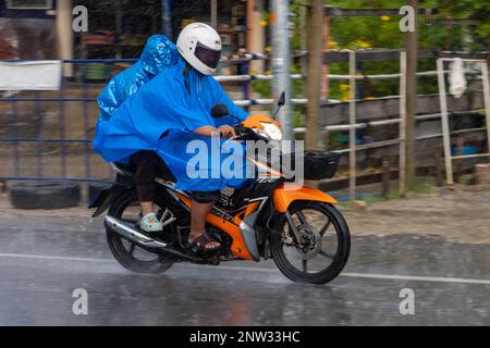 SAMUT PRAKAN, THAILANDIA, 21 2022 SETTEMBRE, coppia in impermeabile guidare sotto la pioggia Foto Stock