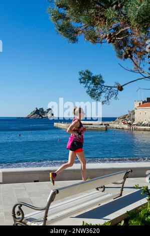 Donna che corre lungo il lungomare di Petrovac, Montenegro Foto Stock
