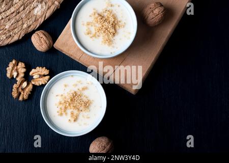 Crema pasticcera fatta in casa con noce, dessert turchi muhallebi su uno sfondo di legno. Crema fatta in casa con noce. Foto Stock