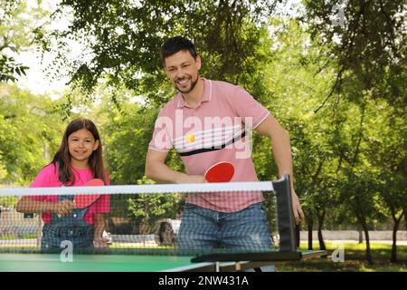 Felice uomo con sua figlia che gioca a ping pong nel parco Foto Stock