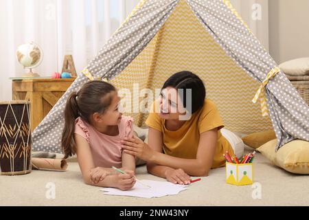 Madre e figlia disegnano a wigwam a casa Foto Stock