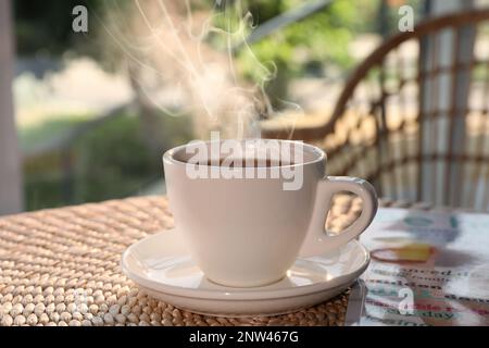 Tazza di delizioso caffè al tavolo di rattan la mattina Foto Stock