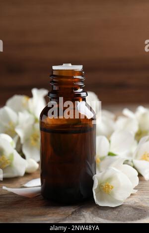 Olio essenziale di gelsomino e fiori freschi su tavola di legno Foto Stock