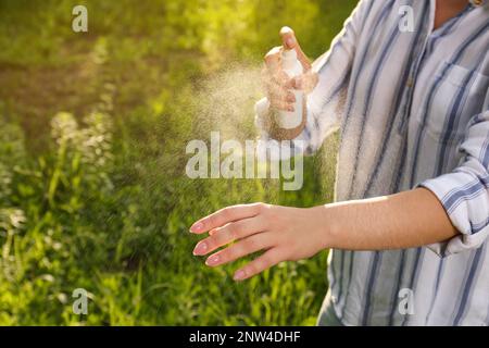 Donna che applica repellente per insetti a portata di mano in parco, primo piano. Prevenzione punture di zecca Foto Stock