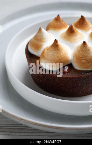 Deliziosa crostata di cioccolato al caramello salato con meringa su tavola bianca, primo piano Foto Stock