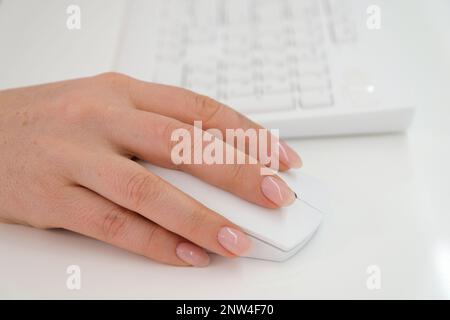 mano femmina su un mouse bianco vicino alla tastiera spazio di sfondo bianco per la pubblicità ufficio lavoro ultima tecnologia pulizia bello Foto Stock
