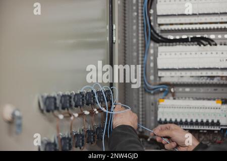 Primo piano delle mani degli elettricisti che lavorano sugli interruttori nella sala di controllo Foto Stock