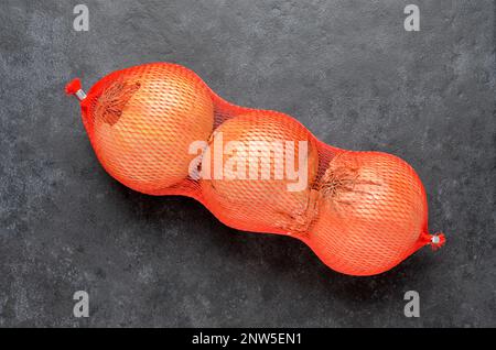 Tre cipolle marroni nella confezione Net Retail dall'alto Foto Stock