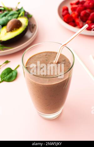 Colazioni salutari, frullati a base di fragole congelate, avocado e banana, proteine della piselli e semi di lino, foglie di insalata, frullati in un bicchiere Foto Stock