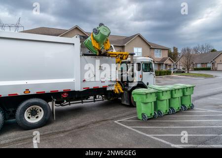 Ripresa orizzontale di un camion dei rifiuti che preleva e scarica i contenitori dei rifiuti residenziali. Foto Stock