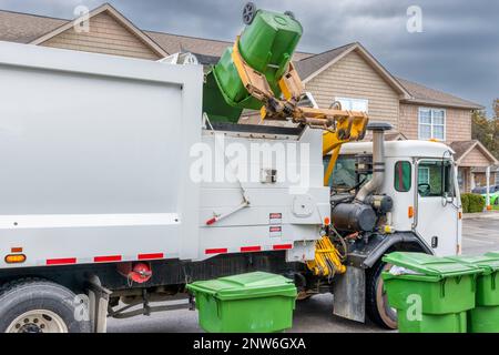 Colpo orizzontale del braccio meccanico su un moderno camion di rifiuti che scarica la spazzatura senza aiuto. Foto Stock