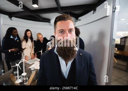 ritratto di uomo d'affari hipster in abiti eleganti con teamwork sfocato sullo sfondo. Scatto grandangolare. Foto Stock