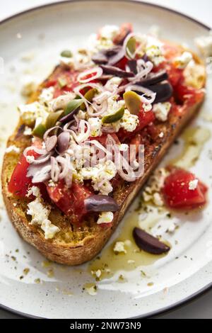 Dakos insalata tradizionale greca insalata con fette biscottate di orzo o pane ammollato e croccante, condita con pomodori succosi, formaggio feta, cipolle, olive, e un Foto Stock