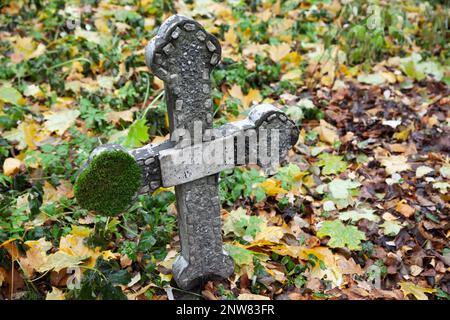 Croce di cemento abbandonata con muschio che cresce su di essa, vecchi dettagli tomba Foto Stock