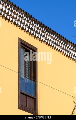 Intricate file di Génoise lavato in bianco contrastano con una parete in stucco giallo brillante su un edificio a San Cristobal de la Laguna a Tenerife Foto Stock