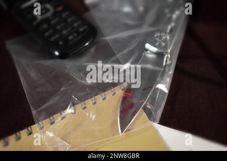 Un coltello a penna colorato con sangue in un sacchetto di plastica trasparente. Prove di giustizia Foto Stock