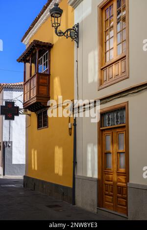 Un tradizionale balcone in legno delle Canarie sul lato di un edificio giallo luminoso in Calle Viana, San Cristobal de la Laguna Foto Stock