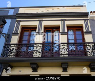 Un balcone ornato in ferro battuto sulla facciata di un edificio giallo pallido in Calle Viana, San Cristobal de la Laguna, Tenerife. Foto Stock