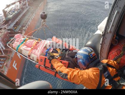 Coast Guard Petty Officer 1st Class Alex Morris, un tecnico meccanico dell'aviazione, salta un uomo di 48 anni in una Air Station Kodiak MH-60 Jayhawk elicottero 220 miglia a sud di Dutch Harbor, Alaska, 11 gennaio 2023. L'equipaggio dell'elicottero MH-60 Jayhawk sollevò il paziente dalla nave container FPMC 33 di 550 piedi e lo trasportò in sicurezza a Cold Bay per un trasferimento ala a ala con il personale LifeMed Alaska che trasportò il paziente a un livello superiore di assistenza medica. STATI UNITI Guardia costiera foto di Scott Kellerman. Foto Stock