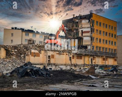 La potenza della distruzione: L'escavatore giallo demolisce le strutture in cemento armato con precisione ed efficienza Foto Stock