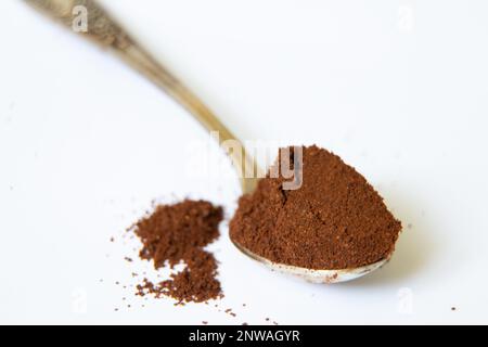 un cucchiaio di caffè macinato su uno sfondo bianco primo piano Foto Stock