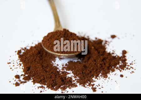 un cucchiaio di caffè macinato su uno sfondo bianco primo piano Foto Stock