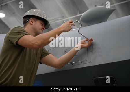 STATI UNITI I manutentori dell'aeromobile dell'aeronautica militare assegnati alla 119th Wing svitano un pannello su un Mietitore mq-9 per accedere al controllo di potenza in preparazione di una rotazione di marcia durante la Cope North 2023 presso la base dell'aeronautica militare Andersen, Guam, 9 febbraio 2023. Cope North è un'opportunità modello per espandere gli impegni con i nostri alleati e partner. Foto Stock