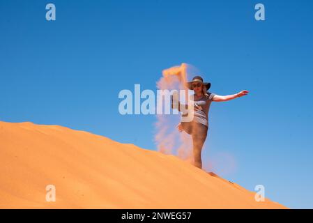 Donna che cammina attraverso il Coral Sand Dunes state Park nello Utah, Stati Uniti. Arancione, deserto paesaggio con bel cielo blu. Foto Stock