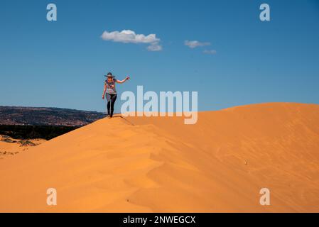 Donna che cammina attraverso il Coral Sand Dunes state Park nello Utah, Stati Uniti. Arancione, deserto paesaggio con bel cielo blu. Foto Stock