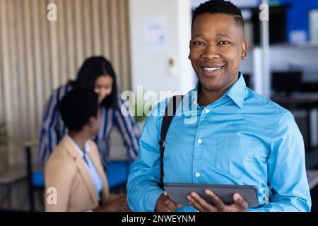 Ritratto di un uomo d'affari afro-americano che guarda la macchina fotografica e sorride in ufficio. Lavorare in ufficio, business, finanza e concetto aziendale. Foto Stock